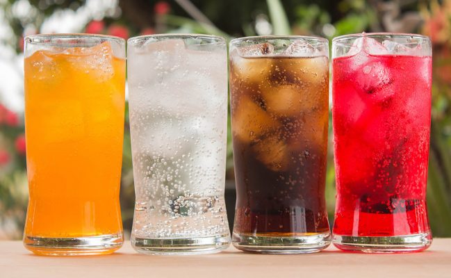 Using Flavours for Drinks. Four glasses of colourful soda with ice.